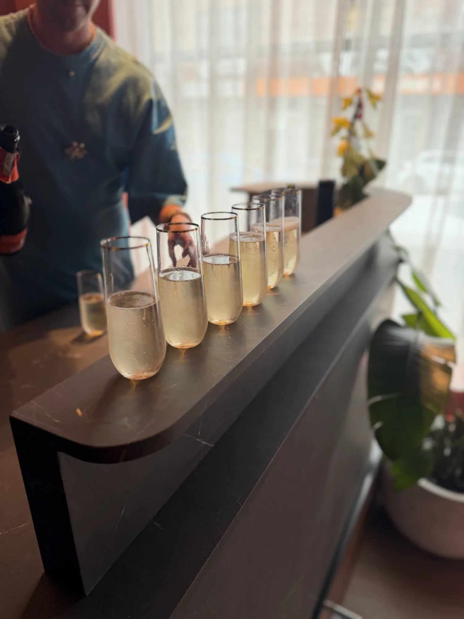 A row of filled champagne flutes on the stone bar
