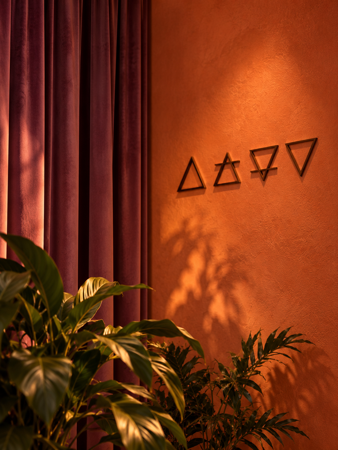 Four element symbols on a terracotta wall beside velvet curtains at Heal Bath House